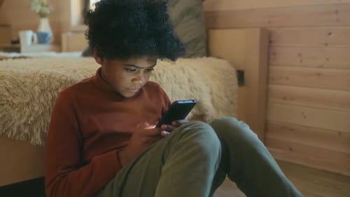Teen Using Mobile Phone While Sitting Indoors