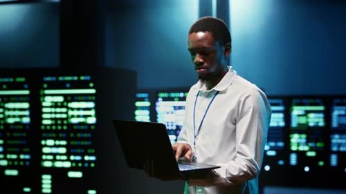 Man Holding Laptop in Server Room