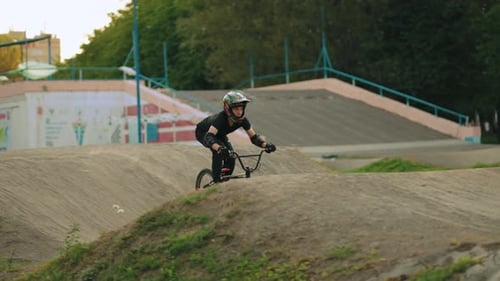 Biker is Riding BMX Bike on Track in Park Young Sporty Man is Practicing Tricks Active Hobby