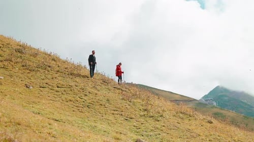 Backpackers in Mountains Man and Woman Walking Together on Slope of High Mount Admiring Landscapes