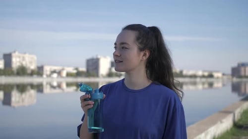 Woman Jogging and Drinking Water in the City