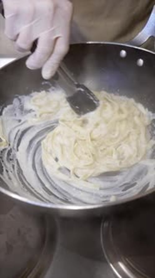 Chef Cooks Fettuccine with Creamy Sauce in Kitchen