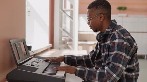 Man Plays Electronic Keyboard in Bright Indoor Setting