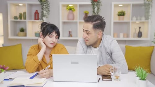 Man and Woman Using Laptop at Table Indoors