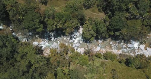 River with huge rocks and water flowing in a forest - bird's-eye drone aerial view near Guatape area