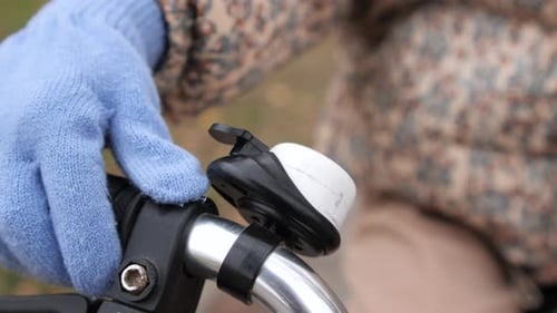 Closeup Child Wearing Blue Gloves is Ringing Bicycle Bell in Autumn