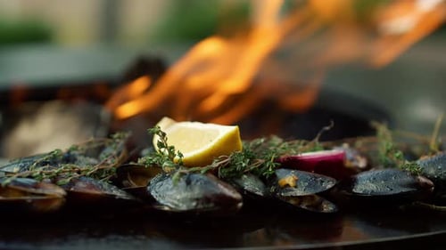 Grilled mussels with lemon and herbs on fire
