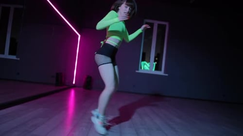 Live Camera A Young Girl in a Bright Stage Costume Dances Twerk in a Dark Choreographic Hall with