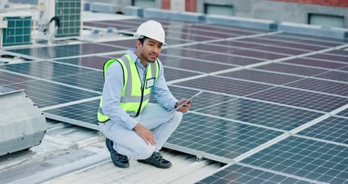 Engineer Inspecting Solar Panels with Tablet on Roof