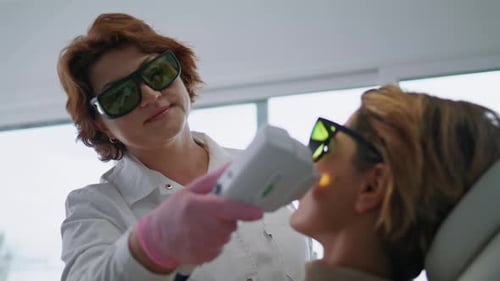 Cosmetologist Dermatologist Using Laser Device for Lifting Client Skin Close Up