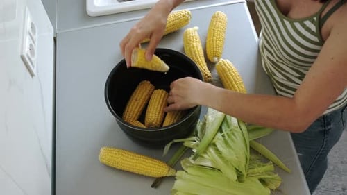 Woman Breaking And Putting Corn In Pot