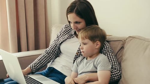 Woman and Boy Watching Laptop Together on Couch
