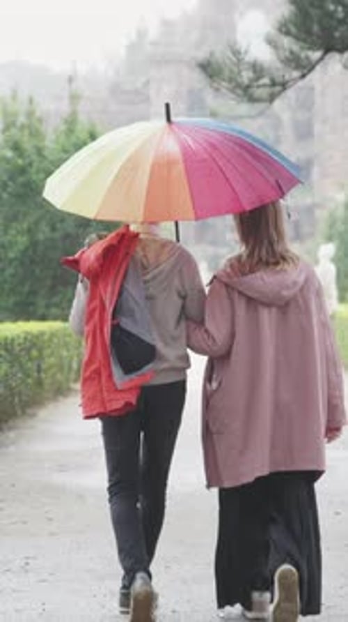 Romantisches Paar spaziert im Regen mit buntem Regenschirm