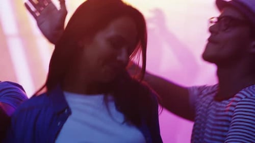 Leute tanzen, haben Spaß und heben die Hände im Nachtclub. Junger Mann und Frau tanzen zusammen.