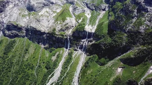Majestic Waterfall Cascading Down Mountainside in Lush Green Valley