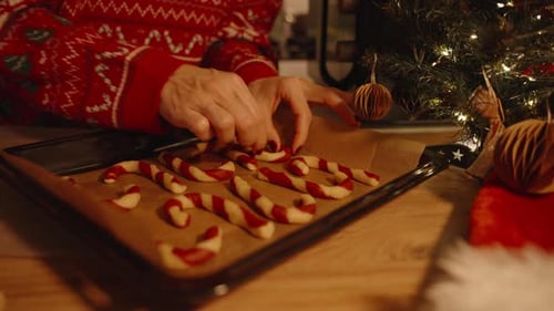 Close View of Candy Cane Dough on Tray with Woman's Hands in Background and Christmas Tree Beside