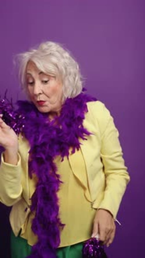 Senior Actress Posing with Purple Feather Boa on Solid Background