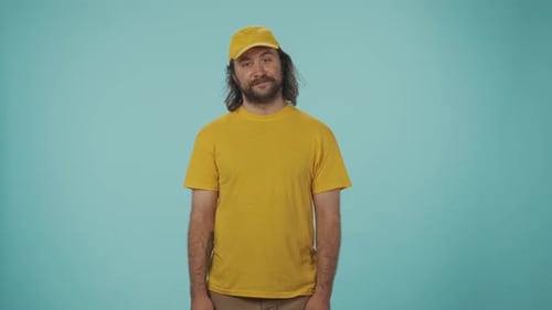 Delivery Man in Yellow Uniform Catches and Taps a Box with Fragile Stickers Placed All Over the