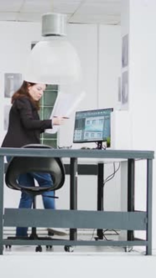 Woman Reviews Paperwork at Computer Desk