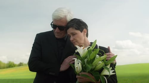 Man Comforting Woman with Flowers in Field