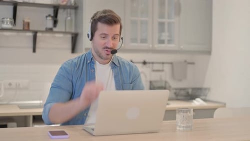 Young Man with Headset Talking with Customers Online in Call Center