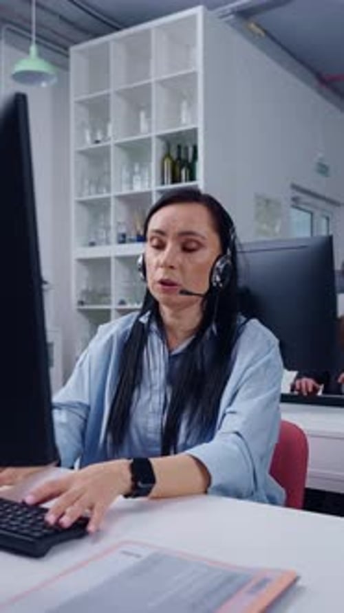 Fokussierter Kundenbetreuer mit Headset arbeitet am Computer im modernen Großraumbüro und tippt unter