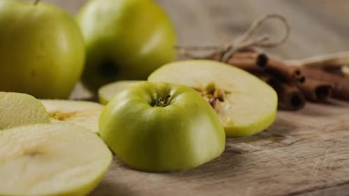 Green Apples with Cinnamon Sticks on Wooden Board