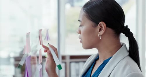 Business woman, brainstorming and writing a note with ideas and planning a strategy in office