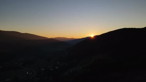 Scenic Aerial View of the Sunset Over the Mountains Range Drone Flies Up and the Sun Appears Behind