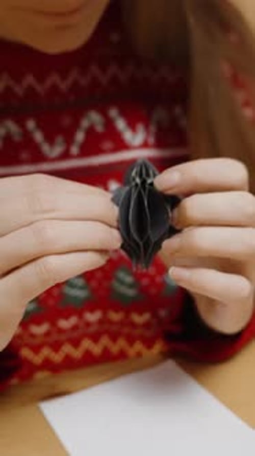 Woman Crafts Paper Christmas Ornament at Table