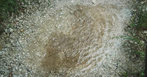 Regenwassertropfen fallen in den Bergen in eine Pfütze. Starker Regen in der Regenzeit. Regentropfen auf