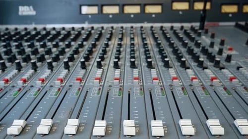 Vintage recording studio mixing desk faders. The music mixer console has faders in the foreground an