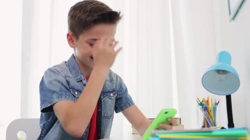 Smiling Boy Using Smartphone at Desk Indoors