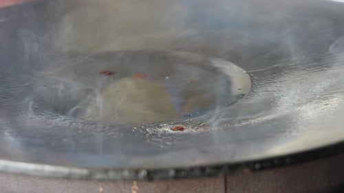 Street food vendor is pan-frying plain paratha roti, a kind of Indian flatbread, in smoking hot oil