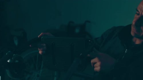Man Adjusting Electronic Lighting Device Indoors at Night