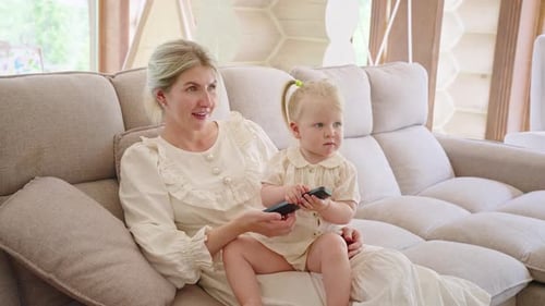 Woman and Child Relaxing on Couch with Remote