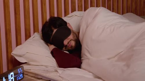 Homme mûr agité en masque de sommeil se réveillant dans son lit perturbé par le bruit