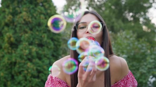 Belle femme heureuse soufflant des bulles de savon dans la rue pendant son enfance à l'âge adulte