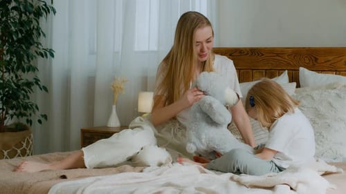 Caucasian Mother Babysitter Mom Play with Teddy Bear with Small Little Cute Daughter Girl in Bedroom