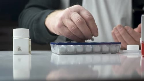 Vieil homme divisant ses pilules hebdomadaires par l'étui à pilules médicinales - Plan rapproché statique
