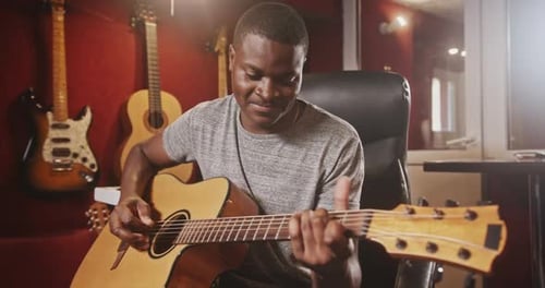 Man Playing Acoustic Guitar in Music Studio