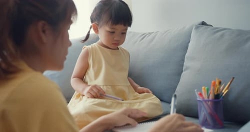 Mother and Child Drawing Together on Gray Sofa