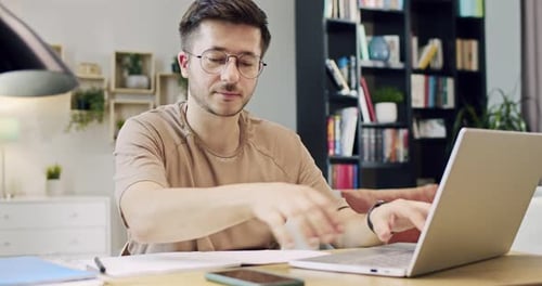 Man Using Laptop and Phone at Desk