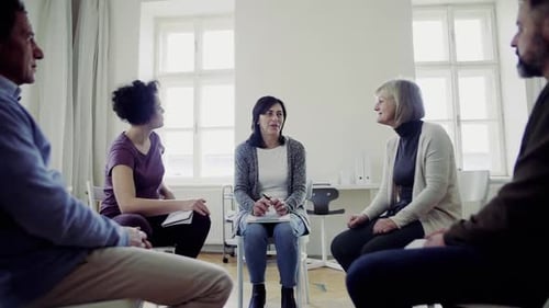 Men And Women Sitting In A Circle During Group Therapy, Talking.