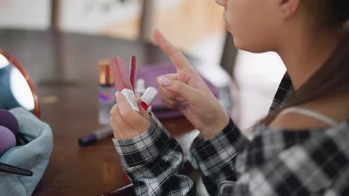 Frau entscheidet sich zwischen Make-up-Produkten, während sie Kosmetik in der Hand hält und untersucht