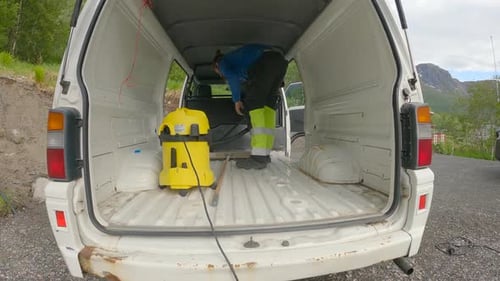 Hombre limpiando una autocaravana con una aspiradora, preparándose para el revestimiento, Van Build.