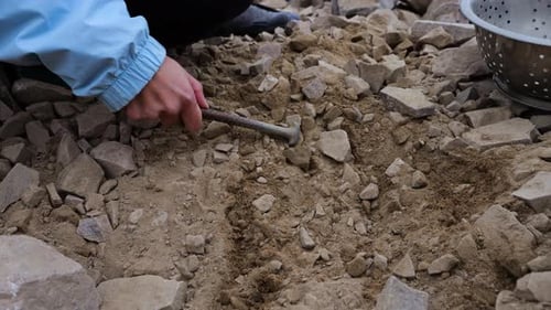 Hand Using Rod to Move Rocks