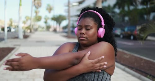 Woman Stretching Arms on Sidewalk Listening to Music