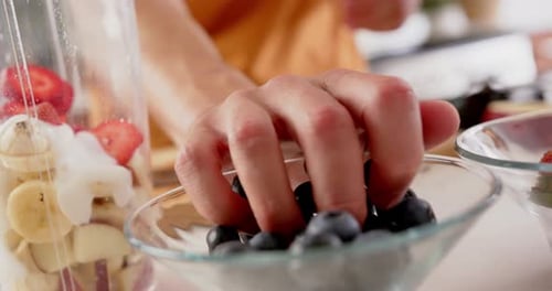Hand of man making smoothie putting chopping fruit in blender, copy space, slow motion