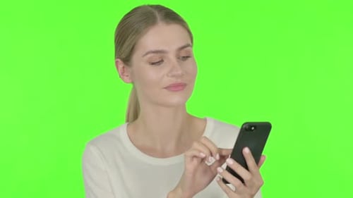 Young Woman Browsing Smartphone on Green Background